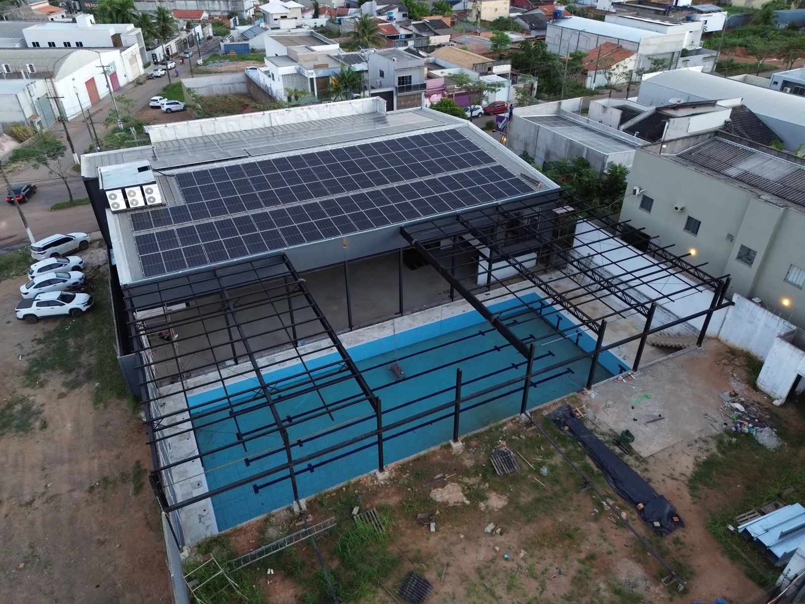Vista aérea da academia com cobertura metálica retrátil sobre a piscina